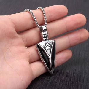 Close-up of a silver spearhead pendant with black enamel inlay and animal paw print