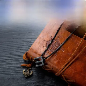 Macro shot of a black stainless steel hollow cube pendant on a vintage leather journal