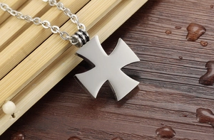 Detailed close-up of a men's matte steel cross pendant with black enamel accents on the ring