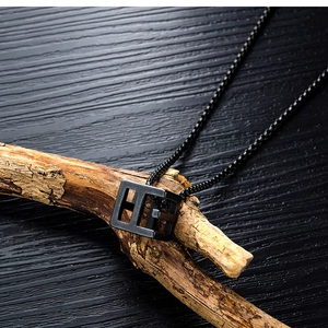 Close-up of minimalist black matte hollow rectangular pendant necklace on a branch