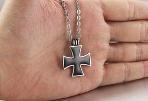 Detailed close-up of a men's stainless steel iron cross pendant with black enamel inlay