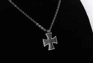 Close-up of a retro iron cross pendant with black matte finish and silver steel chain