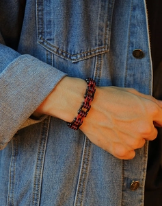 Gros plan d'un bracelet style chaîne de vélo en acier inoxydable noir et rouge
