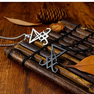 Détail des pendentifs Sceau de Lucifer argentés et noirs sur fond en bois rustique