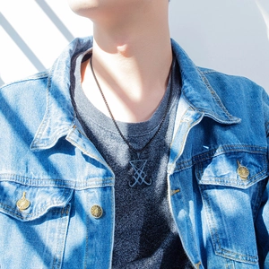 Détail d'un collier avec pendentif sceau de Lucifer noir mat porté sur une veste en jean