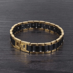 Détail du bracelet magnétique avec maillons en acier noir et or sur surface en bois