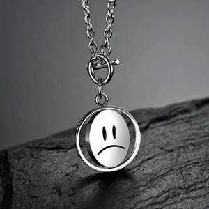 Collier rotatif en acier inoxydable avec pendentif visage triste sur roche noire texturée