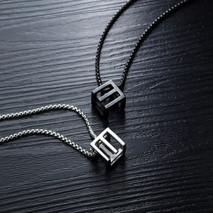 Minimalist stainless steel hollow cube necklaces in silver and black on dark wood