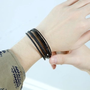 Dettaglio del bracciale multistrato in pelle nera intrecciata indossato al polso