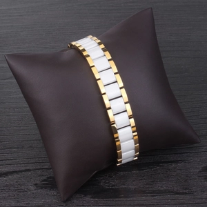 Détail du bracelet magnétique en céramique blanche et acier inoxydable doré sur coussin