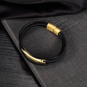 Dettaglio di un bracciale in pelle nera intrecciata multistrato con chiusura magnetica oro