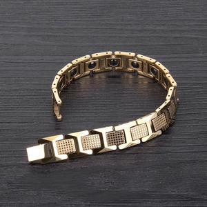 Macro view of gold tungsten bracelet with magnetic inserts on black wood background