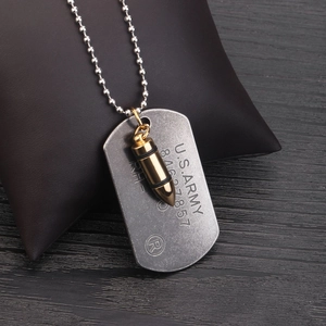 Vintage US Army steel dog tag with golden bullet pendant on dark leather cushion