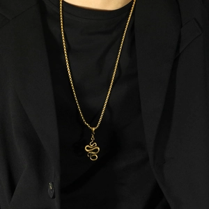 Macro shot of gold snake pendant necklace with realistic scale texture on black suit