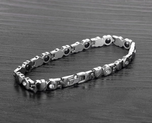 Macro di maglie a cuore in argento con zirconi e magneti su sfondo di legno scuro