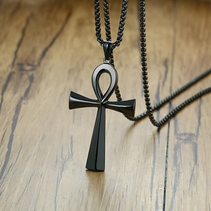 Macro detail of matte black stainless steel Ankh cross pendant on light wooden surface