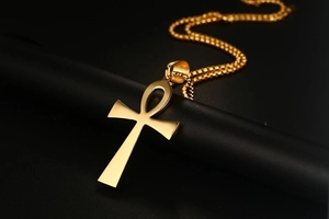 Macro shot of polished gold Ankh cross pendant on round box chain over black display