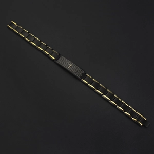 Macro shot of men's black matte bracelet with gold edges and carbon fiber cross inlay