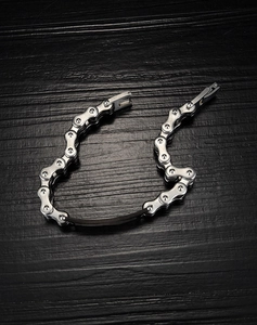 Gros plan d'un bracelet gourmette moto pour homme avec insert noir sur bois sombre