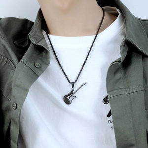 Detailed close-up of a black guitar pendant necklace on a bead chain with military green shirt