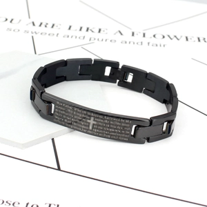 Détail d'un bracelet en acier inoxydable noir avec croix gravée sur un socle en pierre