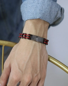 Détail d'un bracelet de chaîne de vélo rouge et noir avec plaque en métal sur un poignet