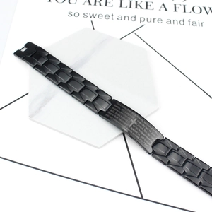 Men's minimalist black stainless steel cross chain bracelet on marble background