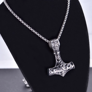 Macro shot of Viking Mjolnir pendant necklace on black display with intricate Norse relief