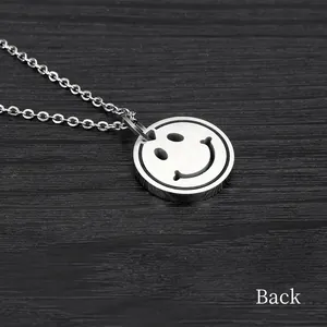 Back view of minimalist stainless steel smiley face pendant necklace on dark wood