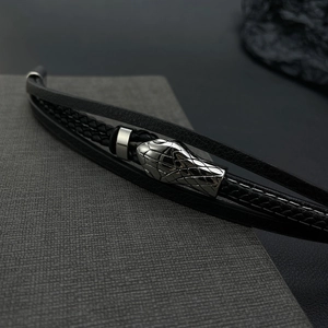 Macro detail of men's leather bracelet featuring a silver metal snake head clasp design