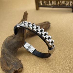 Detail of men's leather bracelet with steel watchband segments on wood background