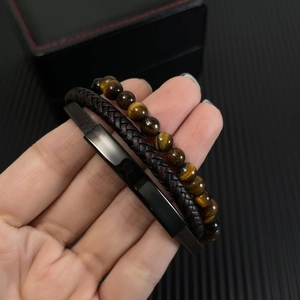 Detail of tiger eye bead bracelet and multilayer leather weave wrap for men