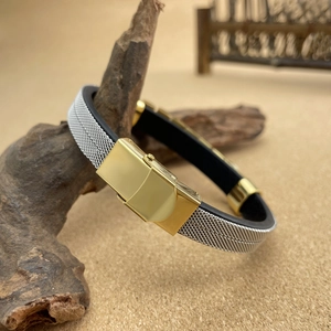 Detail of men's steel mesh bracelet with gold folding clasp on wooden stand
