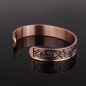 Viking magnetic copper bracelet with vintage carvings on a black reflective surface