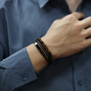 Detail of men's multilayer bracelet set featuring tiger eye beads and braided leather