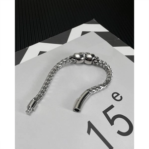 Macro detail of silver-colored woven metal bracelet featuring detailed skull head clasps