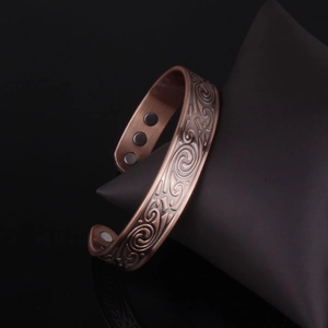 Vintage copper magnetic therapy bracelet with embossed scroll patterns on black cushion
