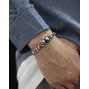 Close-up of double skull heads on a silver-tone braided wheat chain men's bracelet