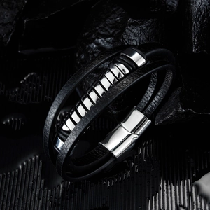Bracelet multicouche en cuir noir pour homme avec anneaux en acier sur fond de roche sombre