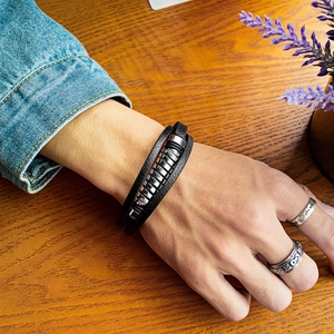 Bracelet multicouche en cuir pour homme avec anneaux en acier sur fond en bois