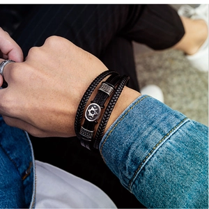 Detail of multi-layer leather bracelet with silver hexagram charm on a male wrist