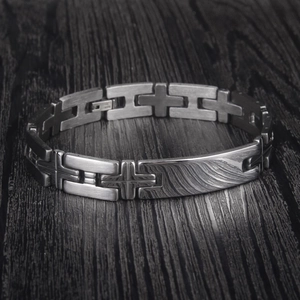 Men's stainless steel cross bracelet with wave texture pattern on a dark wood background