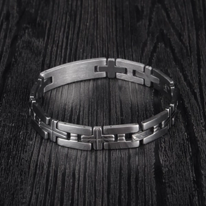Men's matte stainless steel link bracelet with embossed cross design on wooden background