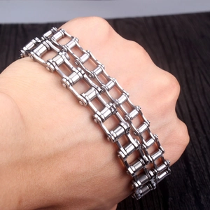 Détail du bracelet chaîne de vélo argenté à double rangée porté au poignet sur bois