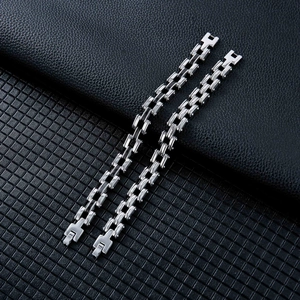 Close-up of silver-tone stainless steel H-link bracelet on black leather background