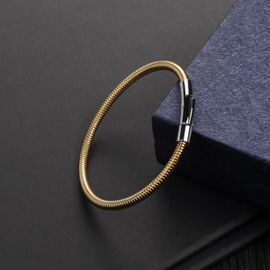 Detail of gold snake chain bracelet with polished silver clasp on minimalist background