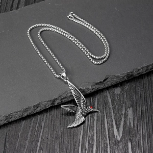Collier pendentif colibri argenté avec détail œil rouge sur fond de pierre texturée