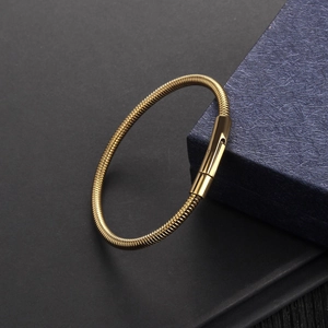 Detail of gold snake bone bracelet with spiral texture and cylindrical clasp on gift box