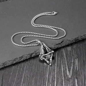 Retro stainless steel Horus Eye triangle pendant with wing details on rock surface