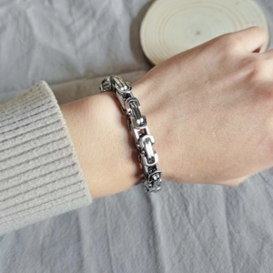 Detail of silver Byzantine chain bracelet on wrist showing thick square woven structure